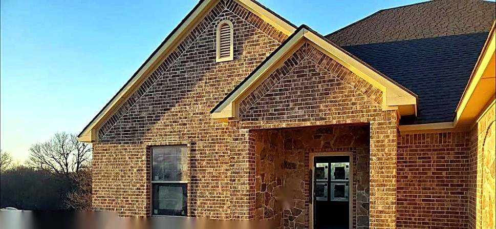 Wide brick and stone home exterior during construction