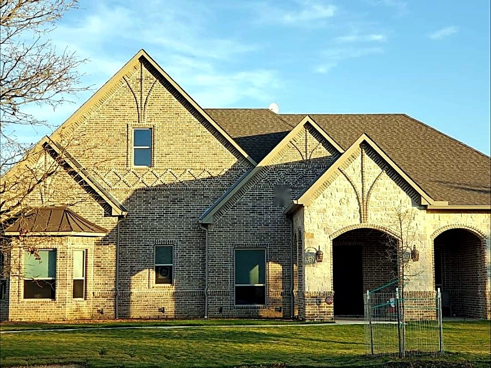 Completed brick and stone home with detailed masonry gables