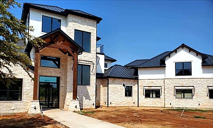 Completed natural stone home with a timber-frame entry