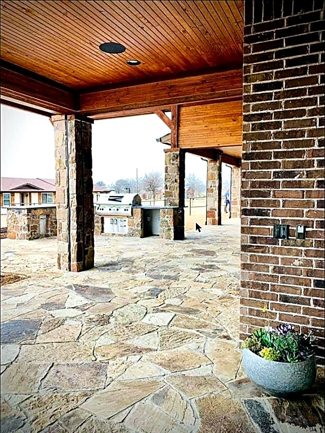 Covered flagstone patio with a brick outdoor kitchen