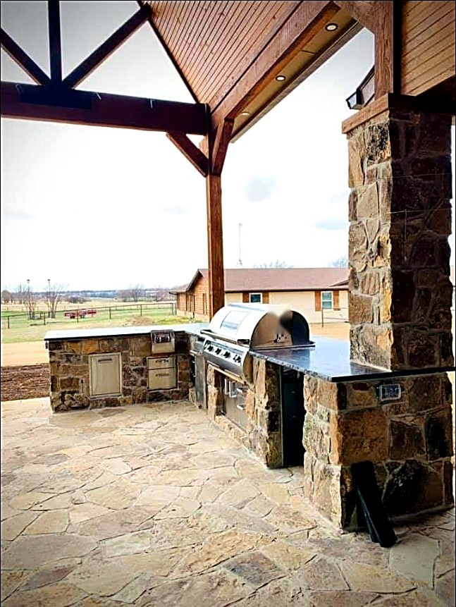 Natural stone outdoor kitchen beneath a timber pavilion