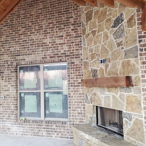 Outdoor brick and stone fireplace with cedar mantel
